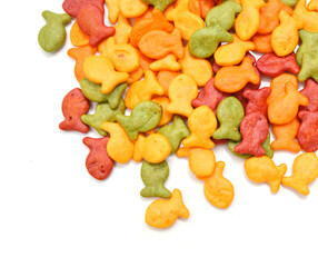 A scattering of yellow fish crackers on white background