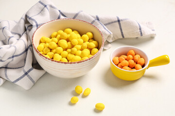 Bowls with chilli and cheese coated peanuts on light background