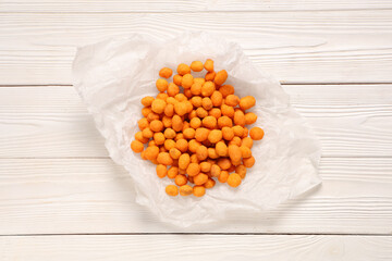 Chilli coated peanuts on white wooden background