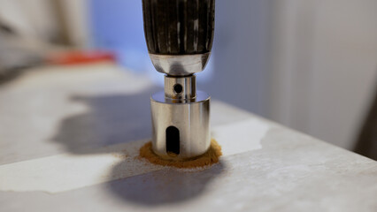 Precision hole saw cutting through white surface, generating clean circular opening while creating...