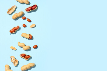 Unpeeled and peeled peanuts on blue background