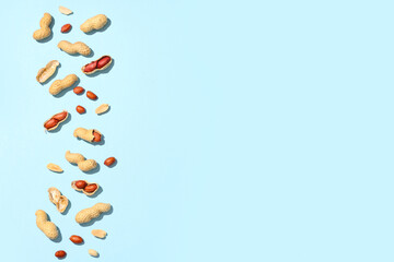 Unpeeled and peeled peanuts on blue background