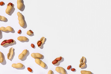 Many unpeeled and peeled peanuts on white background