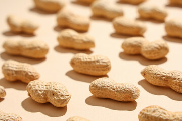 Many unpeeled peanuts on beige background, closeup