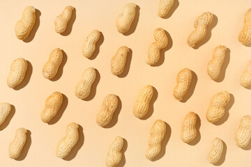 Many unpeeled peanuts on beige background