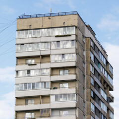 Detailed view of a concrete residential high-rise with enclosed balconies and signs of aging, set...