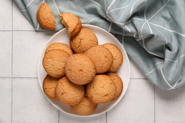 Plate with sweet cookies on white tile background