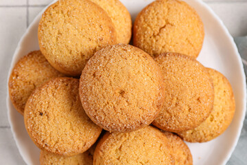 Plate with sweet cookies on white tile background, closeup