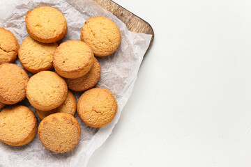 Wooden board with sweet cookies on white background