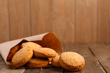 Paper cone with sweet cookies on wooden background, closeup