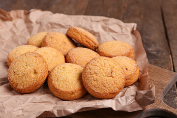 Cutting board with sweet cookies on wooden background, closeup