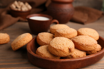 Plate with sweet cookies and cup of fresh milk on wooden background, closeup
