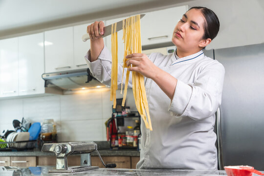 Latin woman chef cutting fresh pasta in a modern kitchen