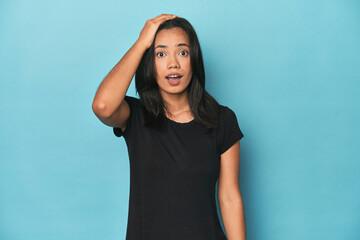 Filipina young woman on blue studio being shocked, she has remembered important meeting.
