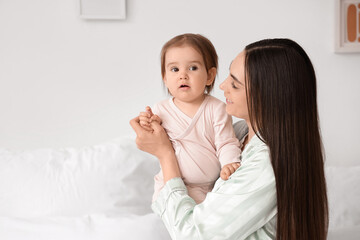 Happy mother with her baby in bedroom