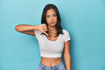Filipina young woman on blue studio showing thumb down, disappointment concept.