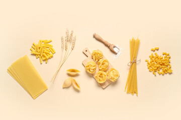 Composition with different types of raw pasta, scoop of wheat flour and spikelets on beige background