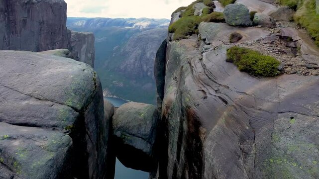 4K drone footage of Kjeragbolten in Norway. Iconic boulder wedged between cliffs over a deep fjord. Famous hiking destination, stunning nature, dramatic mountain landscape and extreme location.