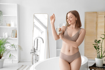 Young woman massaging her hand with brush in bathroom