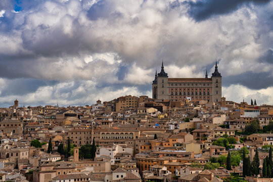 Alcazar of toledo dominating the cityscape under a dramatic cloudy sky