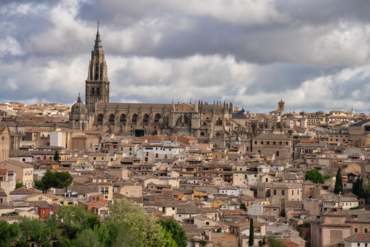 Toledo cathedral towering over the cityscape under cloudy sky