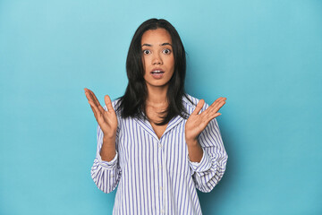 Filipina young woman on blue studio surprised and shocked.