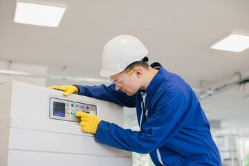 Technician operating industrial control panel pushing button wearing safety equipment