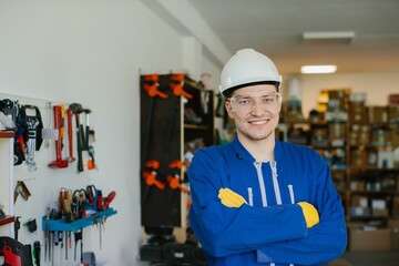 Portrait of smiling engineer wearing hardhat and safety glasses in workshop