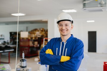 Smiling engineer wearing hardhat and protective glasses in factory