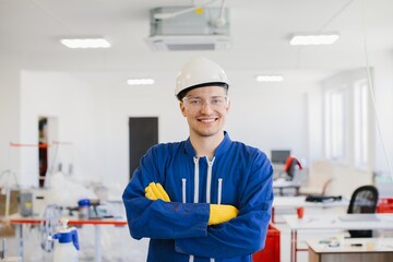 Smiling engineer wearing hardhat and goggles in factory