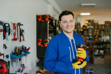 Smiling worker holding cordless drill in workshop