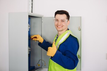 Electrician working on electrical panel and showing thumbs up sign