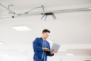 Technician configuring wireless router using laptop in modern office building