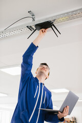 Technician installing wireless router while holding laptop