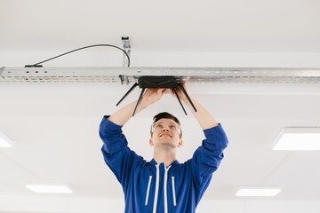 Technician installing wireless router on ceiling in office building