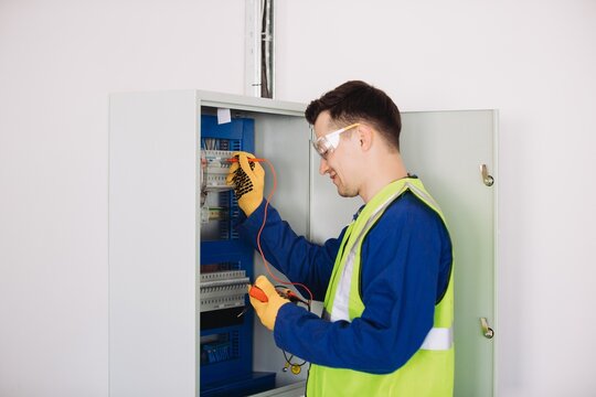 Electrician performing maintenance check on electrical panel using multimeter