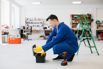 Repairman opening toolbox in workshop with protective glasses and gloves