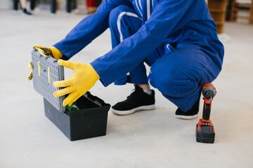 Worker opening toolbox with cordless drill nearby