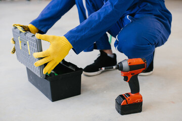 Construction worker opening toolbox with cordless drill nearby
