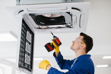 Technician repairing air conditioner using electric screwdriver