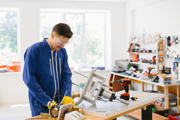 Technician assembling machine part in workshop: concentrated engineer working on project