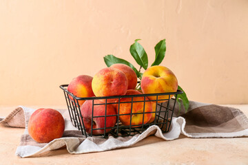 Basket with sweet ripe peaches on beige background