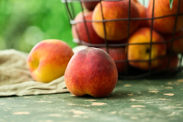 Basket with sweet ripe peaches on green table outdoors