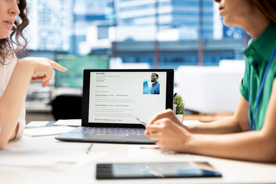 HR manager looking at CVs on tablet to vet selected applicants and ensure their skills match role needs. Headhunters in startup workspace reading resumes on device, assessing candidate work experience