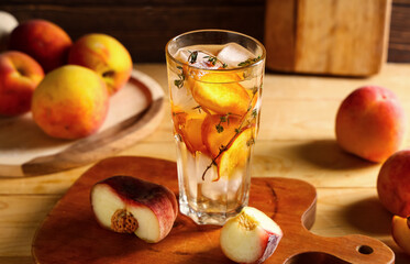 Glass of fresh peach lemonade with thyme and fruits on wooden background