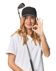 Young blonde golfer in studio cheerful and confident showing ok gesture.