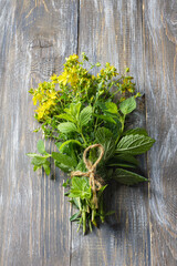Bundle of fresh St. John's wort and mint tied with twine on rustic wooden table. Organic medicinal herbs used for natural healing, herbal remedies and and herbal tea