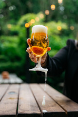 A person is holding a glass of beer with foam on top