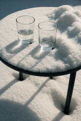 Obraz premium Winter sunlight on glasses of water sitting on snow-covered table