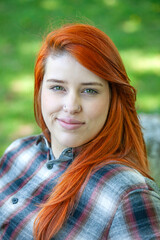 Close up portrait of beautiful young woman with dyed red hair and nose piercings.